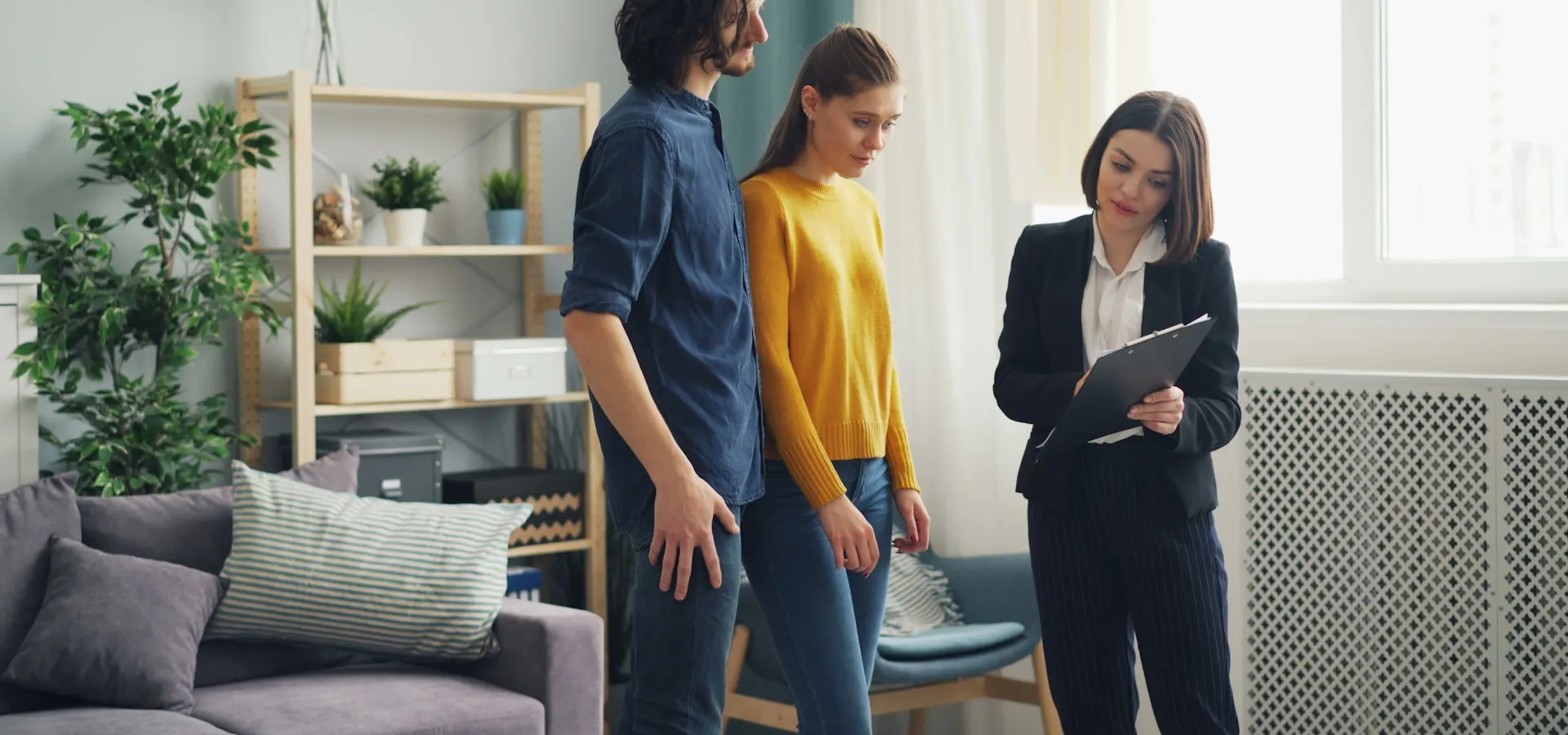 A real estate agent showing a home to a young couple