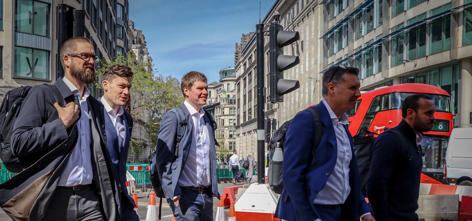 Business professionals walking through a London street with a red double-decker bus